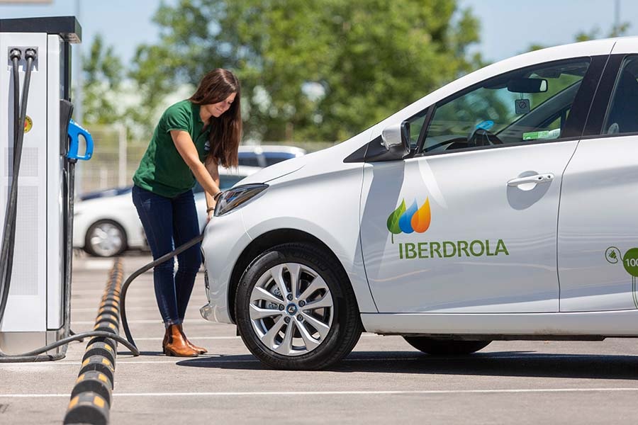 mujer llena coche eléctrico en electrolinera