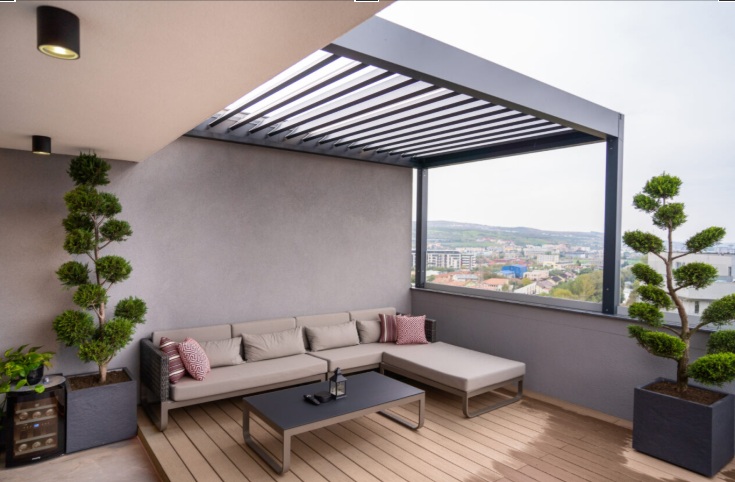 Terraza moderna con pérgola de aluminio y plantas para ganar privacidad en el exterior.